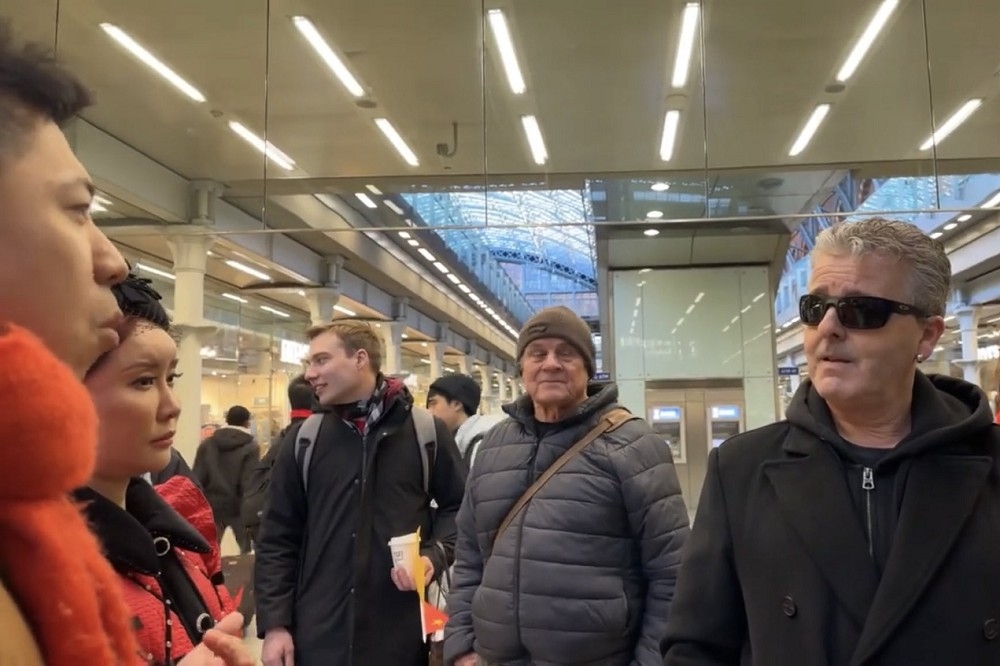 一群中國民眾（左）要求英國街頭藝術家卡瓦納（右）改變表演場地，引發爭吵。（取自@addicted2newz）